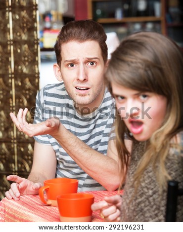 Disgusted young woman with frustrated man at cafe