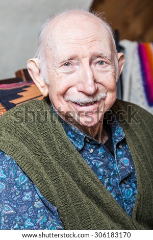 Older gentleman in green vest smiling into the camera