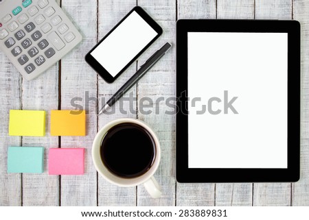 Digital tablet computer with sticky note paper and cup of coffee on old wooden desk. Simple workspace or coffee break with web surfing.