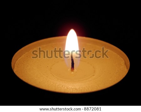Closeup of burning candle on black background