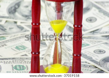 Sand glass with gold sand on dollar background