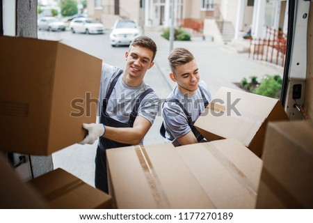 Two young handsome smiling movers wearing uniforms are unloading Stock foto © 
