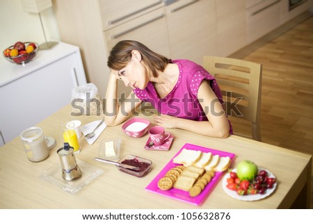sad female model thinking unhappy in front of very rich breakfast