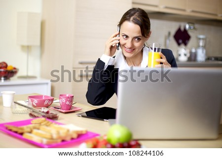 Happy businesswoman talking on the phone during breakfast at home in the morning