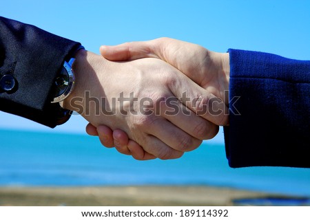 Business hands shaking in front of sea and ocean