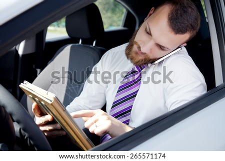 Handsome man talking on the phone while texting email with ipad tablet