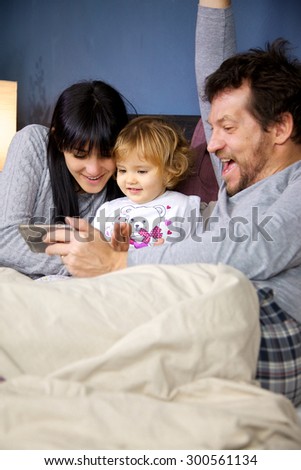 Happy little girl in bed with father and mother playing