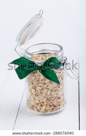 The oat flakes in opened jar on wooden table.