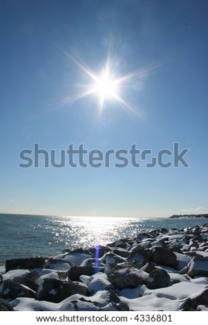Lake from the snow covered coast with a reflected sun