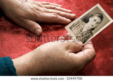 Old hands keep a photo of a young woman