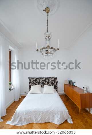 Bright bedroom with white walls and spartan chandelier