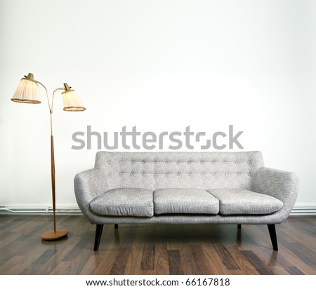 A modern gray sofa and a retro lamp with two heads against bright background on wooden floor