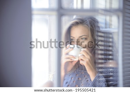 beautiful woman drinking coffee in the morning sitting by the window.