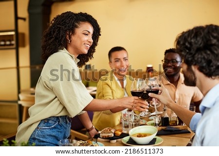 A group of tipsy friends toasts with red wine during a dinner party at a restaurant. Foto d'archivio © 