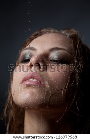 Portrait of a girl\'s face which water flows on a dark background.