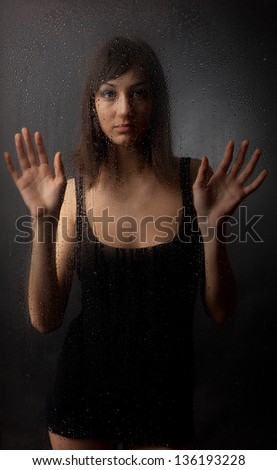 The brunette in a black dress for a wet glass on a black background.