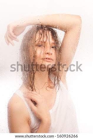 Portrait of a girl with wet hair, with a wet glass on a white background.