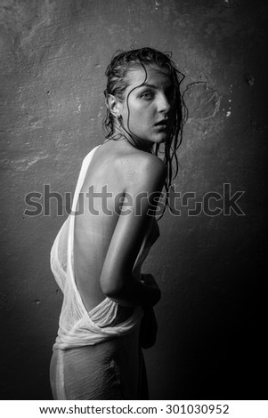Naked girl in a wet white cloth on a gray background.