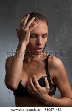 Wet woman in black lingerie on the gray background.