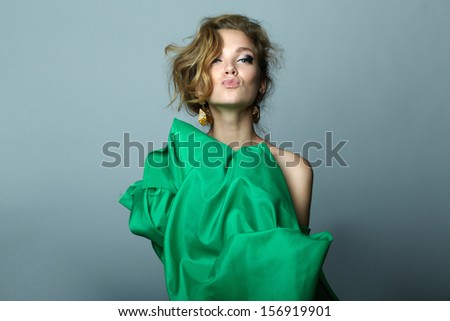 High fashion. Emotional portrait of a beautiful sexy blonde with long hair in green dress