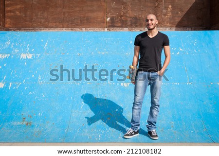 Skateboarder portrait standing on half pipe at skate park.