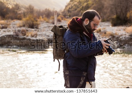 a man hiking and looking at the screen of a digital single lens reflex
