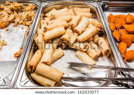 a lot of spring rolls in the food warmer of a self service restaurant