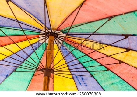a colorful rainbow colored beach umbrella seen from below
