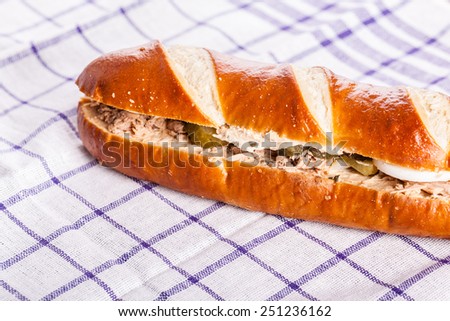 studio shot of a delicious tuna sub sandwich with cucumbers over a simple tablecloth