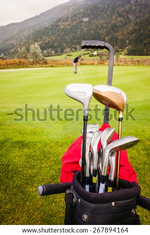 a wheeled golf bag full of golf clubs of a vibrant golf course