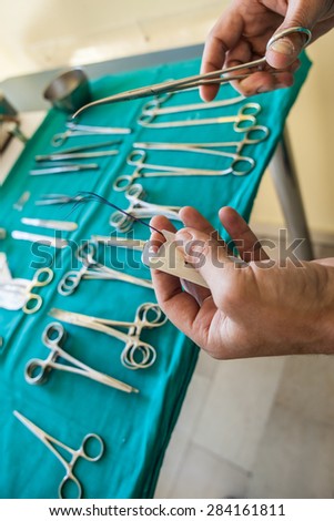 the hands of a surgeon preparing the thread for the stitches