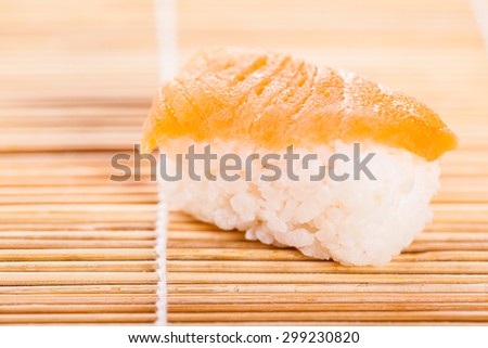 macro shot of a salmon nigiri sushi on a wooden bamboo sushi mat
