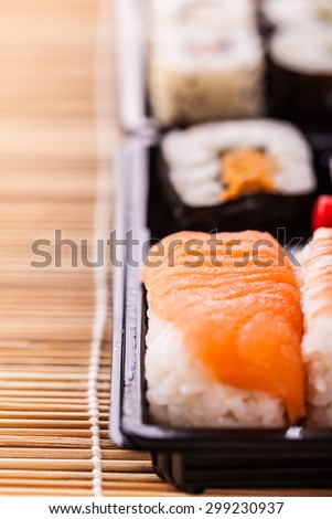 a sushi take away plastic tray box on a wooden bamboo sushi mat