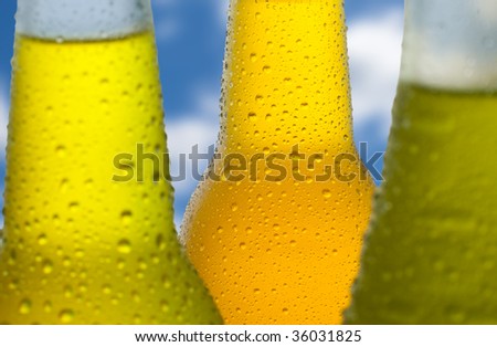 Close up shot of wet bottles with tropical drinks with a sky in the background