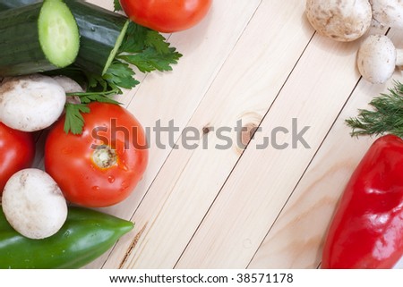 Overhead of table top with fresh veggies around the corners with empty space for text