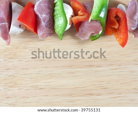 Overhead close up image of meat sticks on wood bread board with space for text