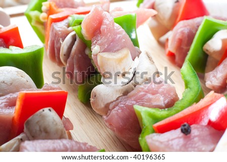 Close up shot of skewer with fresh veggies and raw pork meat