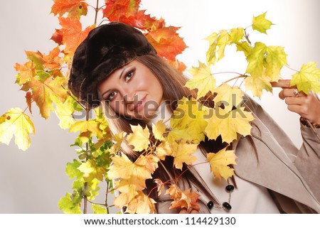 Portrait of beautiful girl with autumn leaves on the color background