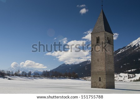 Winter scene at Lake Reschen with sunken gray steeple. Lake Reschen is an artificial lake located in the western portion of South Tyrol, Italy, near the Reschen Pass.