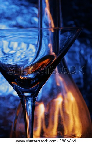 glass & bottle with flame inside over blue background