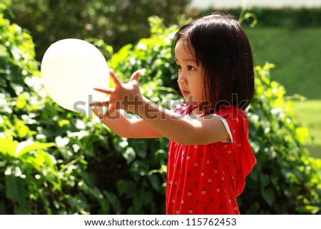 Cute girl playing balloon in garden.Isolated in garden background.