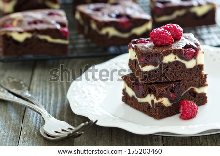 Cheesecake brownies with raspberry stacked on a plate
