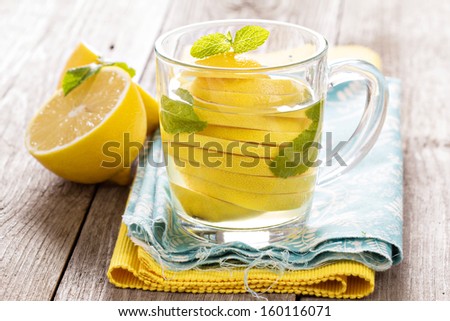 Tea with mint and whole lemon in a transparent cup. Natural medicine concept.