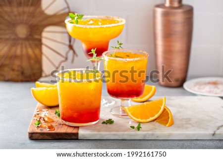 Tequila sunrise margarita cocktail in different glasses with ice, refreshing summer drink