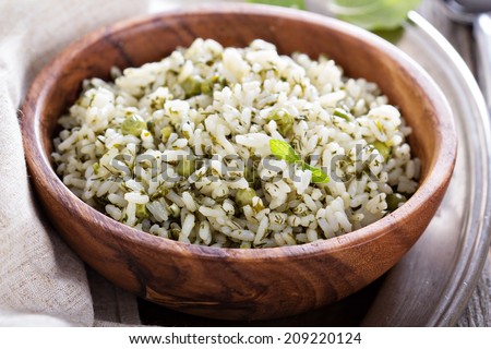 Green rice with herbs in wooden bowl