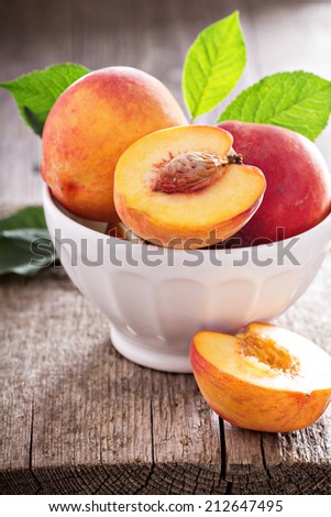 Fresh peaches in a bowl with one cut