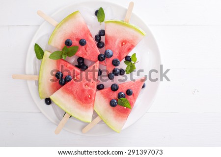 Fresh watermelon popsicles with blueberries cut on ice top view
