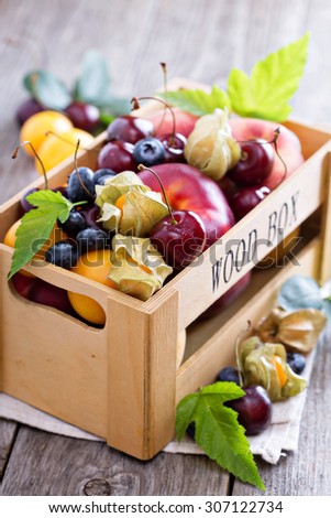 Fresh fruits cherries peaches plums in a wooden crate