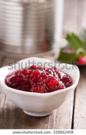 Cranberry sauce in small dish with metallic jar in the background