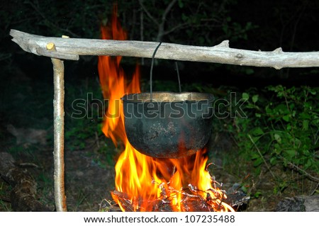 Boiling water in metal pot on fire in the forest